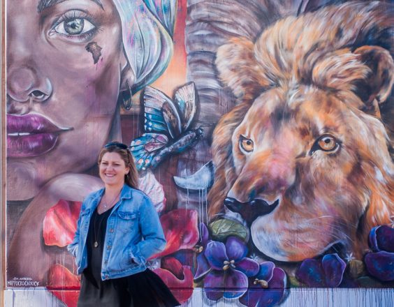 Woman smiling next to mural