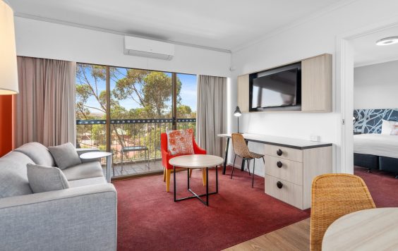 Desk, tv and sofa beside balcony in Plaza Hotel room