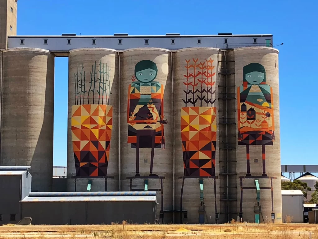 A row of grain siloes with colourful graphic mural art painted on the side, near the country town of Merredin.